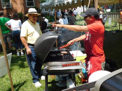 people stand around a grill